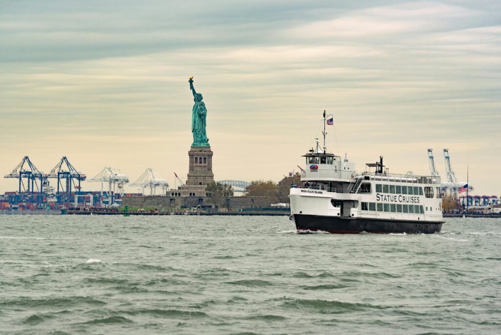 A ferry cruises past the iconic Statue of Liberty in New York Harbor, USA.
